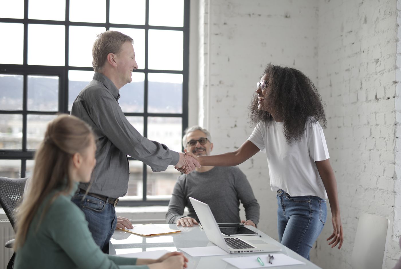 Two professionals shaking hands across a desk