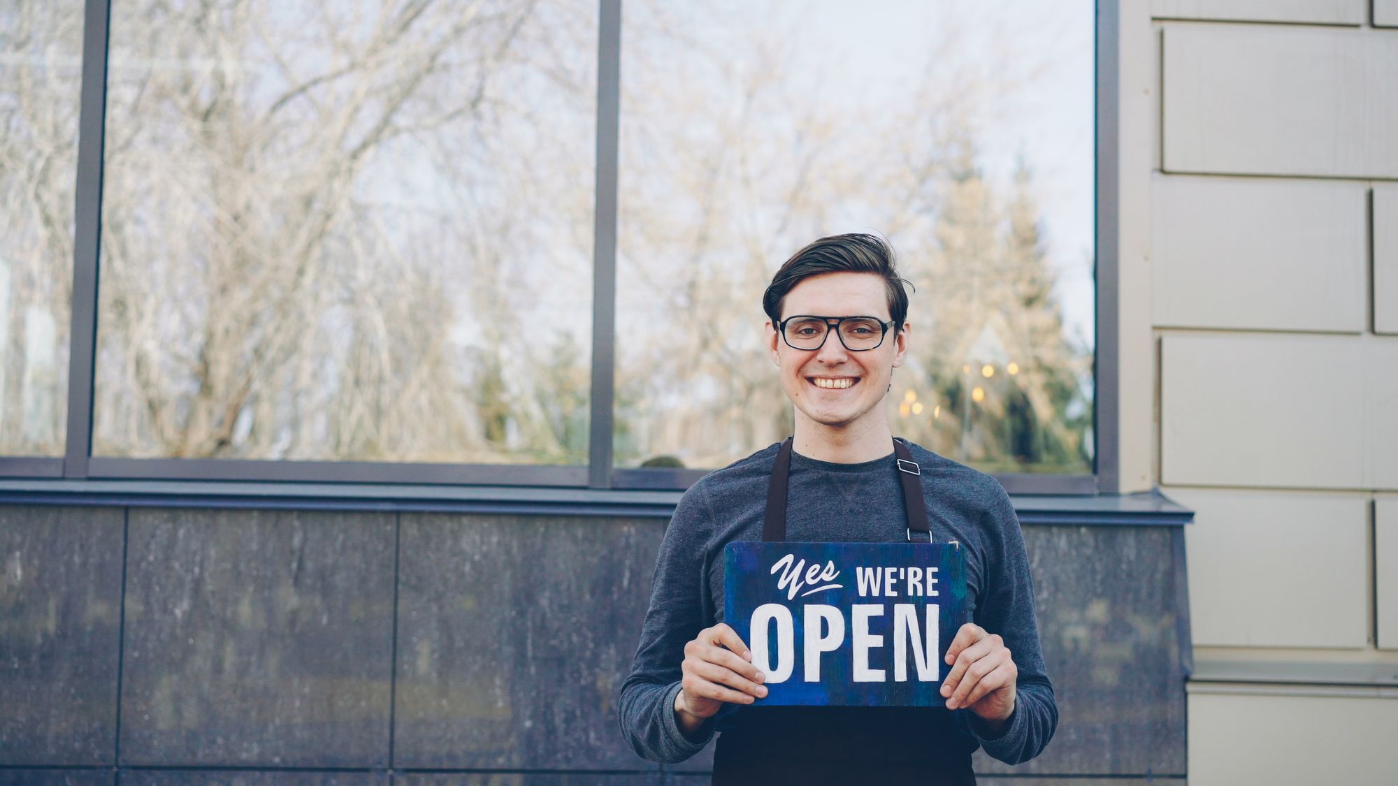 Small business owner holding an open sign outside her shop